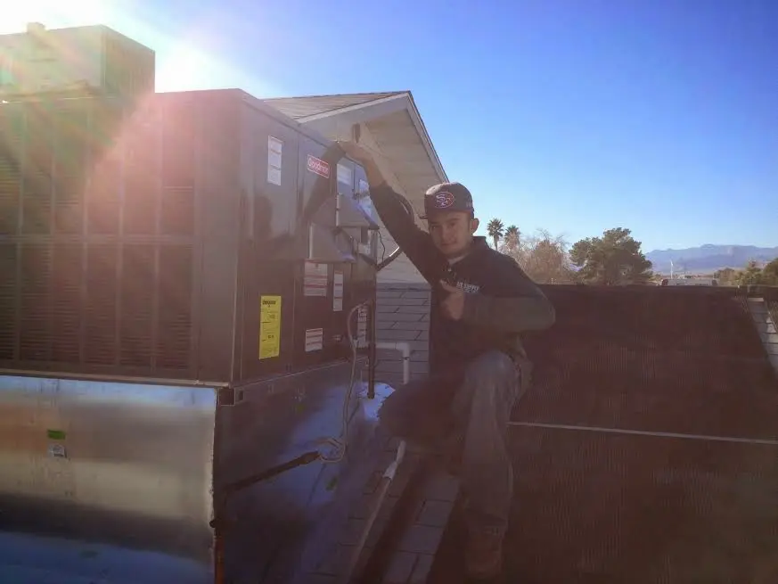 HVAC technician performing Air Duct Cleaning on a rooftop unit in Houston