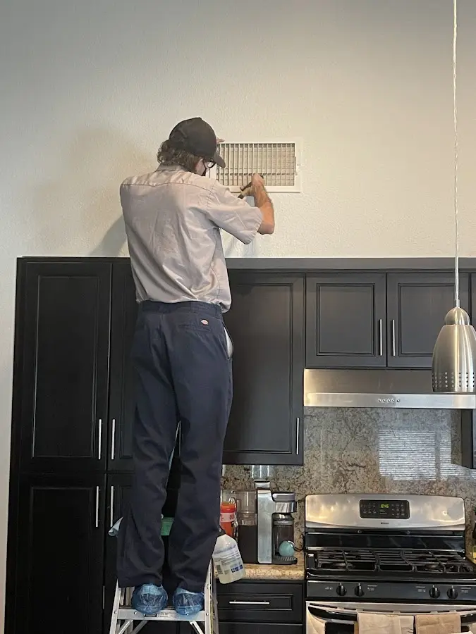Technician inspecting an air vent during HVAC service in Houston